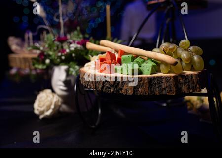 assorted cheese and grapes on a wooden stand at the event. Stock Photo