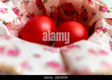 Two red dyed Easter eggs in a bowl with floral paper napkins. Stock Photo