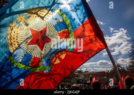 Moscow, Russia. 1st May, 2022. View of a flag and an arms of Lugansk People's Republic during a rally marking International Workers' Day held by the Russian Communist Party by the Karl Marx Monument in Teatralnaya Square in central Moscow Stock Photo