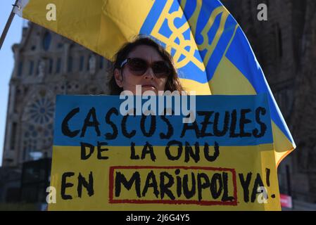 A protester holds a placard reading 'Cascos Azules de la ONU en Mariupol' (United Nations Peacekeepers in Mariupol) during a demonstration against Russia's invasion of Ukraine. Around three hundreds demonstrators, mostly Ukrainians, gathered in front of the famous Sagrada Familia basilica in Barcelona, to demand a green corridor in Mariupol and peace for their country. Stock Photo