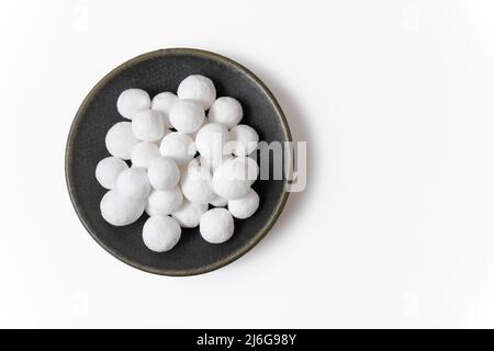 White delicious sugar balls in a gray plate isolated on a white background. Close-up, top view. Stock Photo