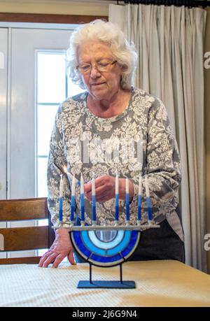 Jewish grandmother lights the candles on her glass menorah Stock Photo