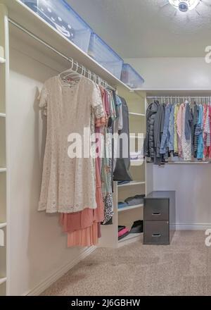 Vertical Walk in closet with organized hanging and stacked clothes and ...