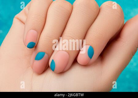Close up womans hand with summer manicure on blue background. Manicure design trends Stock Photo