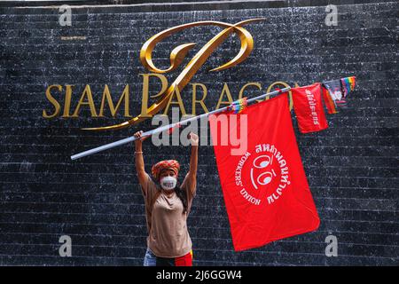 Worker's Union demonstrator holds a flag in front of Siam Paragon department store, one of the most luxurious department store in Bangkok during the demonstration. The Worker’s Union group held a parade on Labor Day in Bangkok, Thailand. The parade was joined by various groups such as; Thai Workers group, Myanmar workers group, and pro-democracy group. They gathered at Ratchaprosong Road then marched to Pathumwan intersection, Demonstrators demanded for welfare, fair rate payment, and also democracy (included Thailand and Myanmar). (Photo by Varuth Pongsapipatt / SOPA Images/Sipa USA) Stock Photo