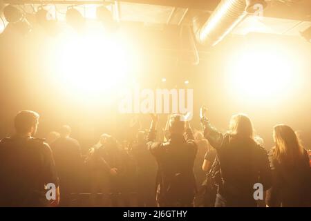 silhouettes of rock concert crowd in front of bright stage lights, text space Stock Photo