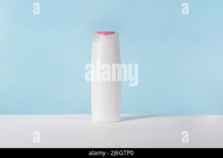 Shampoo white cosmetic bottle mockup on blue background. Hair product, bath soap or lotion packaging. Plastic cosmetics tube front view advertising Stock Photo