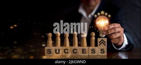 business man hand holding light bulb on wood block with Word success, business teamwork concept with innovation and inspiration, innovative technology Stock Photo