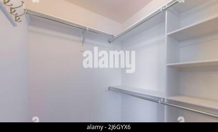 Panorama Small walk-in closet with shelves and metal rods below Stock ...