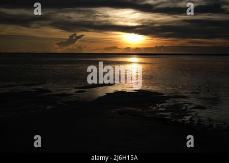 Late sunset over Andaman sea and sandy beach, with heavy clouds incoming for a night storm Stock Photo