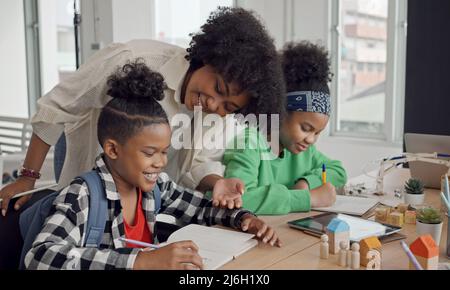 African American female teacher standing with pupils teaching writing lesson in modern classroom. Stock Photo