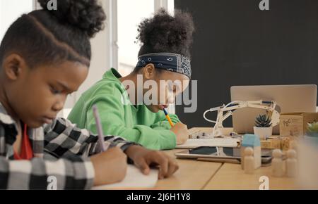 Student in international preschool writing a book together in Elementary School Class, Pupils enjoying studying in classroom. Stock Photo