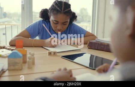 Student in international preschool writing a book together in Elementary School Class, Pupils enjoying studying in classroom. Stock Photo