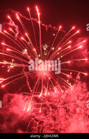 A fireworks explosion and a smoke trails in a night sky Stock Photo