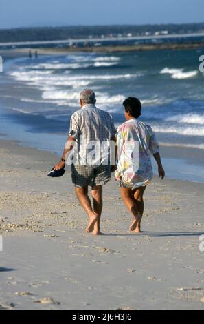 MIDDLE-AGED COUPLE IN THE LATE AFTERNOON WALKING ALONG A NEW SOUTH WALES BEACH, AUSTRALIA. Stock Photo