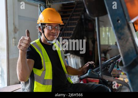 A Worker driving a forklift in warehouse. Stock Photo