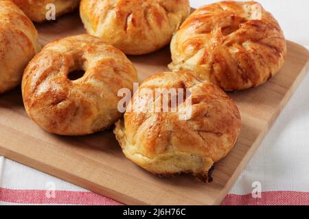 Baked pies laid out on a wooden kitchen board Stock Photo