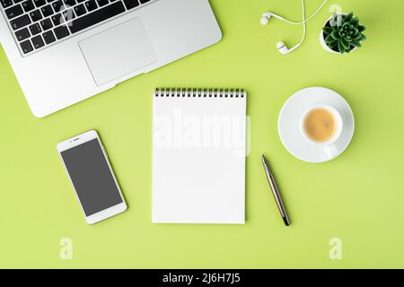 Concept of modern workspace. Notebook, smartphone, coffee cup, laptop and earphones on green backdrop Stock Photo