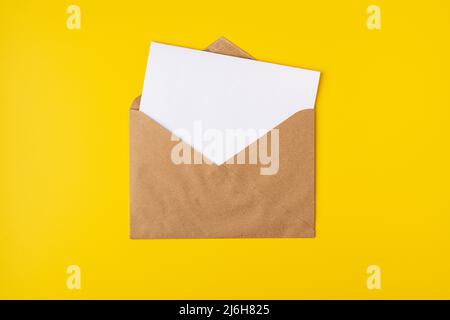 Realistic mockup blank white letter craft paper envelope on yellow backdrop front view, template Stock Photo