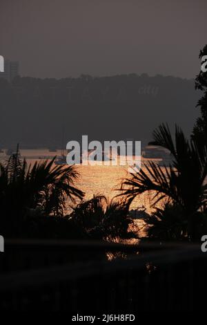 Remote view of bay of Pattaya city, Thailand, brightly lit with setting sun Stock Photo