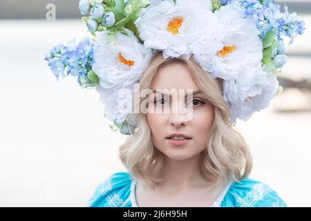 Beautiful young Ukrainian woman with a big beautiful flower wreath on her head looks at the camera. Stock Photo