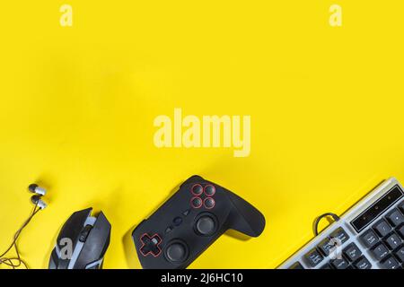 Gaming concept with various gamers devices on bright yellow background - gamepad joystick, keyboard, mouse, headphones. Girls gamer concept with gamin Stock Photo