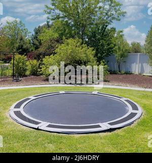 Square White puffy clouds In-ground trampoline on a lawn at the backyard in Utah Stock Photo