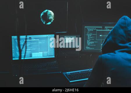 Cyber criminal hacking system at monitors, hacker attack web servers in dark room at computer with monitors sending virus using email vulneraility Stock Photo