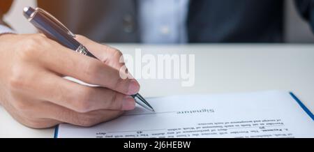 man signing on contract documents after reading, man holding pen and approve on business report. Contract agreement, law and deal concepts Stock Photo