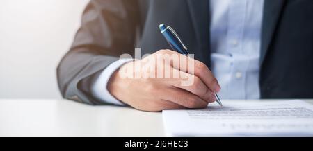 man signing on contract documents after reading, man holding pen and approve on business report. Contract agreement, law and deal concepts Stock Photo