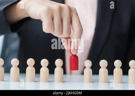 Businesswoman hand pulling leader man wooden from crowd of employees. Toxic People, Human resource management, Recruitment, Teamwork and leadership Co Stock Photo