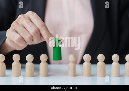 Businesswoman hand pulling leader man wooden from crowd of employees. Toxic People, Human resource management, Recruitment, Teamwork and leadership Co Stock Photo