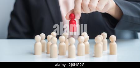 Businesswoman hand pulling leader man wooden from crowd of employees. Toxic People, Human resource management, Recruitment, Teamwork and leadership Co Stock Photo