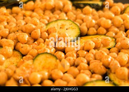 Spiced chickpeas and sliced courgette on a baking tray ready to be put in the oven Stock Photo