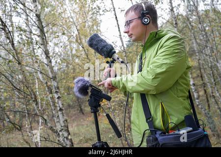 The guy with Shotgun Condenser Microphone and headphones is recording the sounds of nature. Recording Ambient Sounds Stock Photo