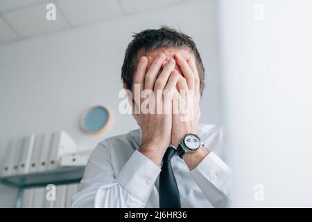 Business failure, businessman covering face with hands and crying in office, selective focus Stock Photo