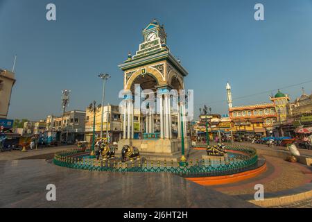 Landmark historic clock tower Chikka Gadiyara aka Dufferin Clock Tower with a fountain set amid a bustling food and flower market, Mysore, India Stock Photo