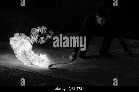 Fascinating and dangerous. Man manipulate with burning poi in dark. Burning fuel and energy. Sparks and lights. Night show. Fire performance. Flirt Stock Photo