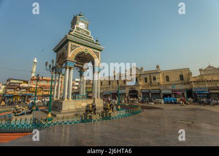 Landmark historic clock tower Chikka Gadiyara aka Dufferin Clock Tower with a fountain set amid a bustling food and flower market, Mysore, India Stock Photo