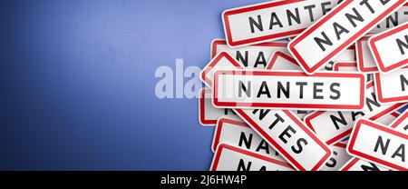 Multiple Nantes city-limit signs on a heap. Nantes is located in the Loire-Atlantique department, France. The typical white city limit sign with a red Stock Photo