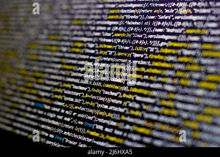 yellow code lines selective focus on the black screen background. blurred white letters side view. Stock Photo