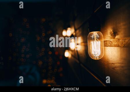 Wooden wall with Edison type bulb and blurred background. Stock Photo