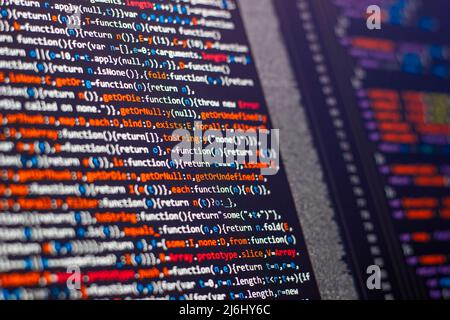 code writing on the office computer screen. red letters intense. web sources creative solutions for digital world. side view of monitor. Stock Photo