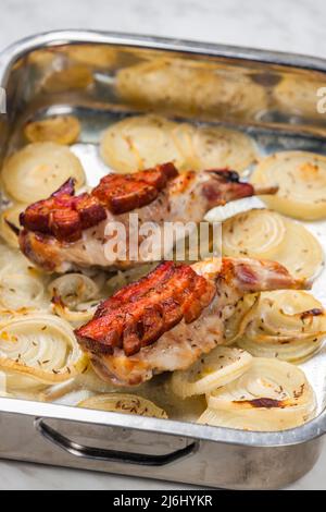 rabbit legs baked with bacon on onion rings Stock Photo