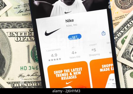 Poltava, Ukraine - April 28, 2022: Nike fashion shopping app logo on mobile phone screen. Business background with dollar money banknotes Stock Photo