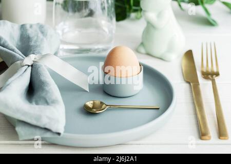 Happy Easter  table setting with traditional  Easter decoration :  white bunny,  natural egg in mint green plate with  gold cutlery. Scandinavian styl Stock Photo