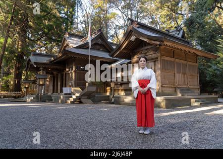 A miko (巫女), or shrine maiden at Takachiho Shrine, a Shinto shrine amongst cedar trees, Takachiho, Miyazaki, Kyushu, Japan Stock Photo