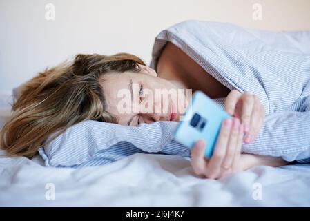 Woman using smartphone in the bed, Social media, Lazy weekend Stock Photo