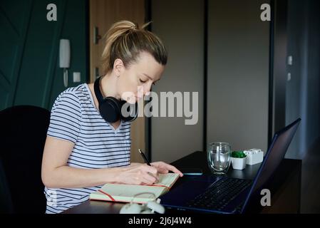 Woman working remotely at home office with laptop Stock Photo