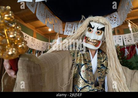 Fujisaki-san, a master of Kagura the Shinto ritual performance telling the stoires of the gods. Wearing the white mask to perform The Dance of Tajikar Stock Photo